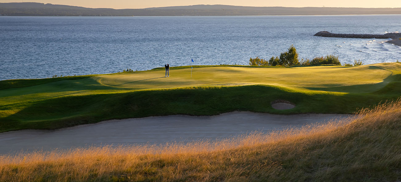 Golfer putting on a green near the coast